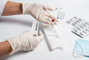 Woman nurse fills the medication organizer in hospital