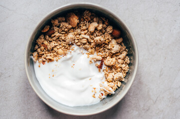 Roasted healthy homemade granola with Gluten Free Rolled oats or porridge oats, variety of chopped nuts and seeds. Portion of granola and kefir or yogurt in bowl