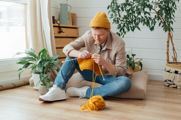 Fototapeta Middle aged man learning knitting on needles. Knitting project in progress. Man learning a new hobby obraz