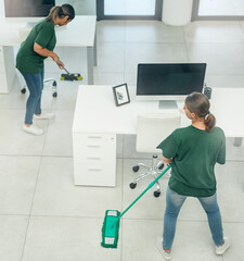 Workplace hygiene is everybodys business. High angle shot of two young woman cleaning a modern...