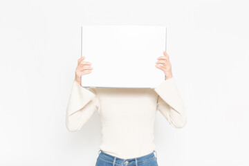 白い壁の前に立って大きなスケッチブックを見せる女性