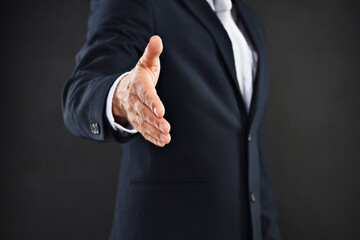 Lets do business. Cropped shot of a businessman extending his arm to shake hands against a black background.