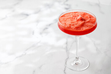 Sunny orange coctail with foam on marble white background with sunny lights. Close up 