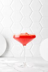 Red alcohol cosmopolitan cocktail in cocktails glass on tile background. Minimalism, sunny and light