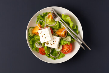 Bowl with salad. Greek vegetable salad with natural feta cheese. Top view, blue backgroubd