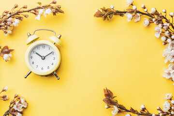 May flowers. Spring blossom and April floral nature with alarm clock on yellow background....