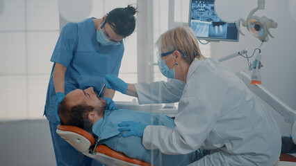 Dentistry team doing teeth consultation to treat patient with toothache, using dental equipment in...