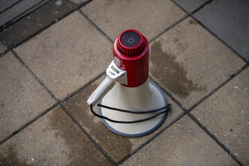 Megaphone isolated on concrete floor background. Megaphone left on ground, after protest and...