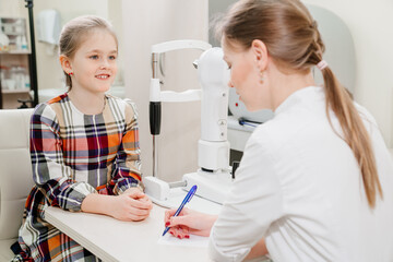 doctor interviews little girl before being examined in ophthalmologist's office.