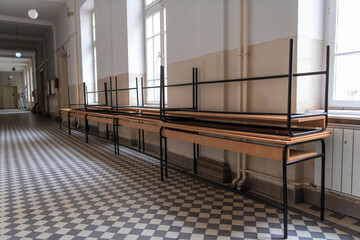 Empty School hallway. School closed due coronavirus, covid19 pandemic lockdown. On-line teaching. Old vintage floors and walls. Rows of tables and chairs.