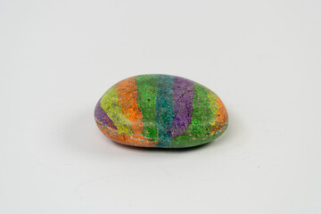 Colorful rock painted by kid for hobby isolated on white background, rainbow color on round rock
