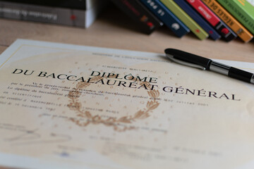 Baccalaureate : close up of a french diploma with some books, the text means general baccalaureate...