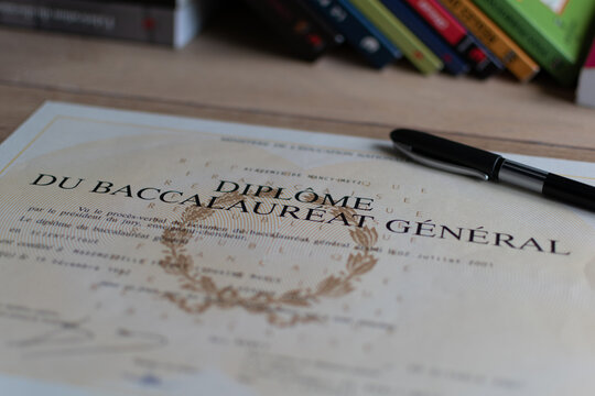Baccalaureate : close up of a french diploma with some books, the text means general baccalaureate diploma