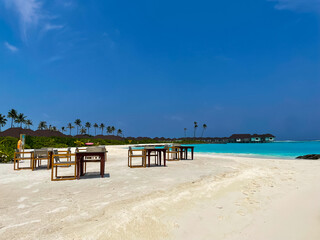 Maldives tropical beach with table and chairs on sea background 