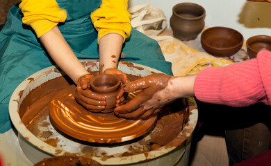 Master, teaches pottery. Hands of a potter making a crock on a circle