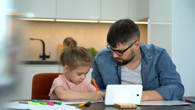 Father and little girl learn to draw watching drawing lesson on tablet on internet. Online education concept. Video tutorial, drawing training.