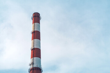 Red and white pipes of a boiler room equipped with a smokeless traffic light. Against the background of the blue sky.