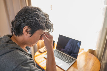 疲れた目をマッサージしているリモートワーク中の男性