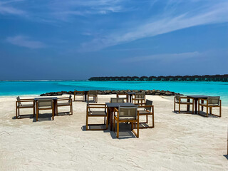 Maldives tropical beach with table and chairs on sea background 