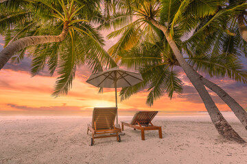 Tranquil tropical sunset scenery, two sun beds, loungers, umbrella under palm tree. White sand, sea view with horizon, colorful twilight sky. Calm relax beach resort hotel. Honeymoon, vacation travel
