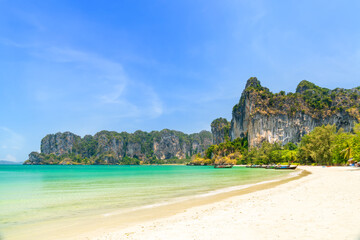 Railay beach west with exotic limestone cliff mountain and longtail wooden tourist boat, Krabi, Thailand
