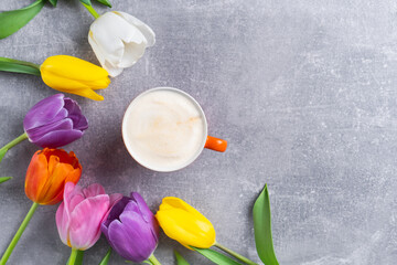 Spring multicolor tulips bouquet and cup of cappuccino on concrete background. Flowers and coffee