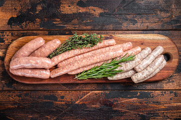 Raw homemade sausages with Beef, pork, lamb and chicken mince meat on a wooden board. Wooden...