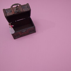 A bride in a white dress on the rim of a wooden coffin on a pink background with copy space. Minimal bride concept.
