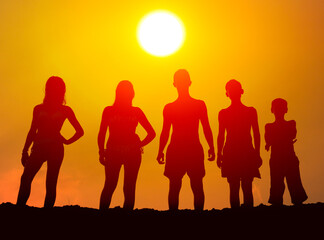 Silhouettes of boys and girls on the beach at summer sunset