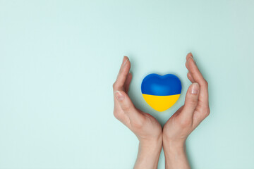 Heart with print the national flag of ukraine in female hand. Flat lay. Copy space.