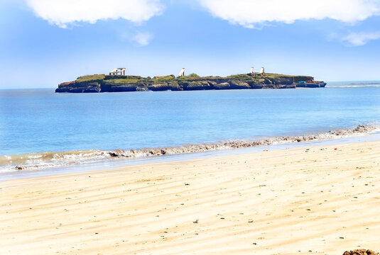 The sandy Nagaon beach with it's blue water in the distance at Diu, Gujarat, India. The brown muddy water and with a sandy beach. view of Arabian. The Indian ocean and iconic font of diu