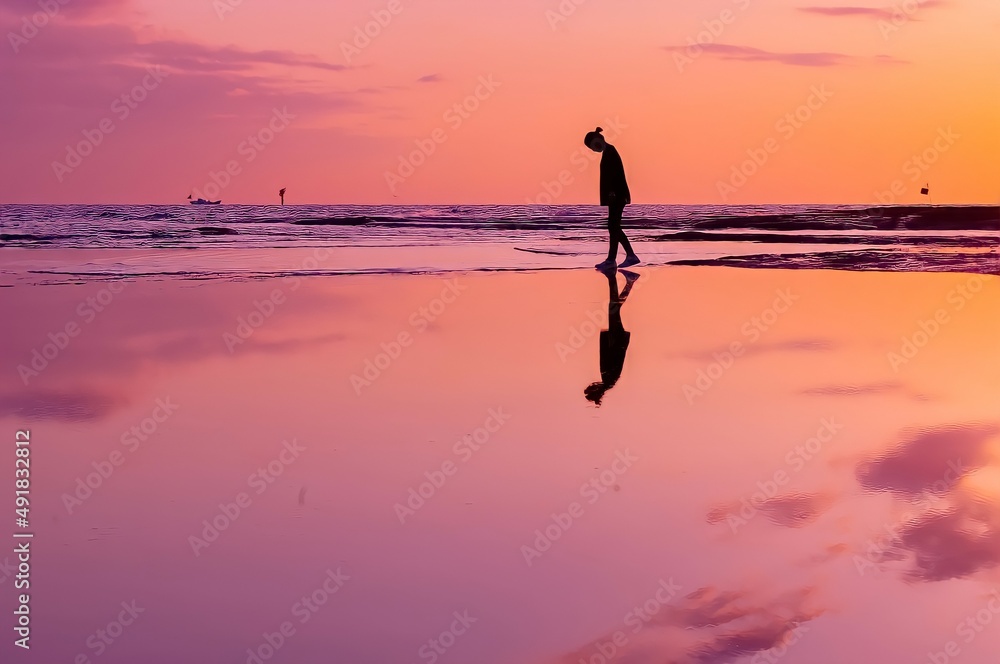 Wall mural silhouette of a person on the beach at sunset