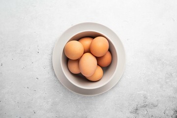 Brown chicken eggs in plate on light background. Concept farm products and natural nutrition. Top view, copy space or empty place for text.