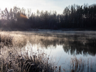 Beautiful early winter morning scenery of landscape of a lake with evaporation fog in temperature below zero caused by cold air passing over warmer water with frozen surroundings