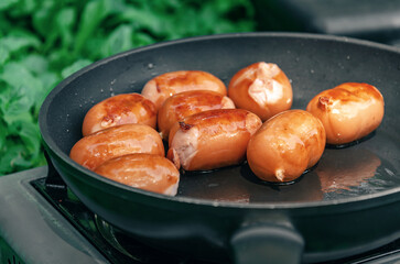 Cooking in nature. Sausages in a frying pan. Side view. Appetizing look.