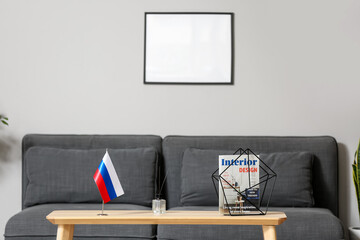 Russian flag on table and blank frame on light wall in room