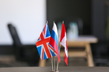 British, Russian and Canadian flags on dark table in office