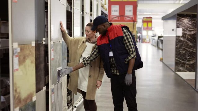 Shop assistant helps the woman to choose marble tile