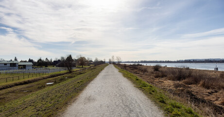 Fototapeta na wymiar Scenic Pathway by Pitt River during a sunny winter day. Taken in Pitt Meadows, Vancouver, British Columbia, Canada.