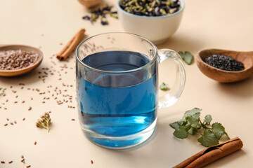 Glass cup of tasty blue tea and flax seeds on color background, closeup