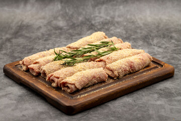 Beef schnitzel on dark background. Delicious raw meat schnitzel prepared with breadcrumbs and white...