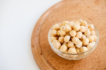 Fresh raw organic chickpeas soaked in water on a white table on a wooden tray. The benefits of legumes. Vegan nutritive proteinaceous food. Taking care of your health. Ingredient of healthy vegan food