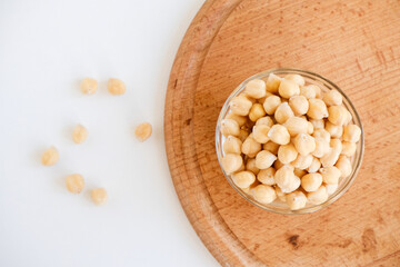 Fresh raw organic chickpeas soaked in water on a white table on a wooden tray. The benefits of legumes. Vegan nutritive proteinaceous food. Taking care of your health. Ingredient of healthy vegan food