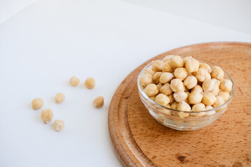 Fresh raw organic chickpeas soaked in water on a white table on a wooden tray. The benefits of legumes. Vegan nutritive proteinaceous food. Taking care of your health. Ingredient of healthy vegan food