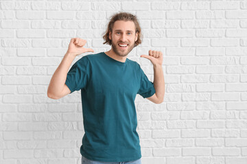 Handsome young man in t-shirt on white brick background