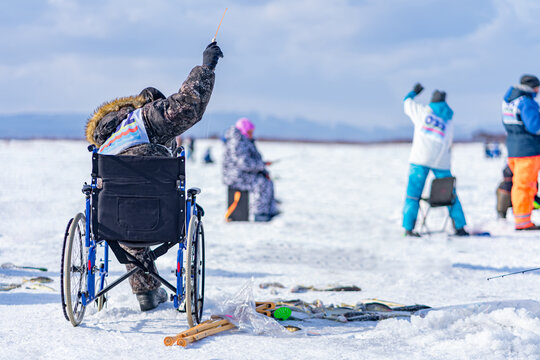 disabled person sitting in a wheelchair catching fish on the ice