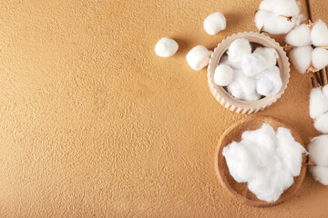Bowls with cotton wool and balls on color background