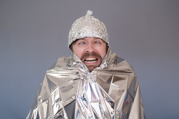 Young man in a cap of foil being afraid and stressed.
