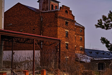 Stary zabytkowy , przemysłowy budynek z czerwonej cegły . Dawna fabryka ( może młyn) z napisem  na ścianie : " PALENIE WZBRONIONE " . W zimowej porze, tuż przed obfitymi opadami śniegu ( śnieżycą ) . © Grzegorz