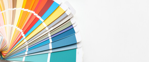 Color guide close up. Assortment of colors for design. Colors palette fan on white concrete wall...